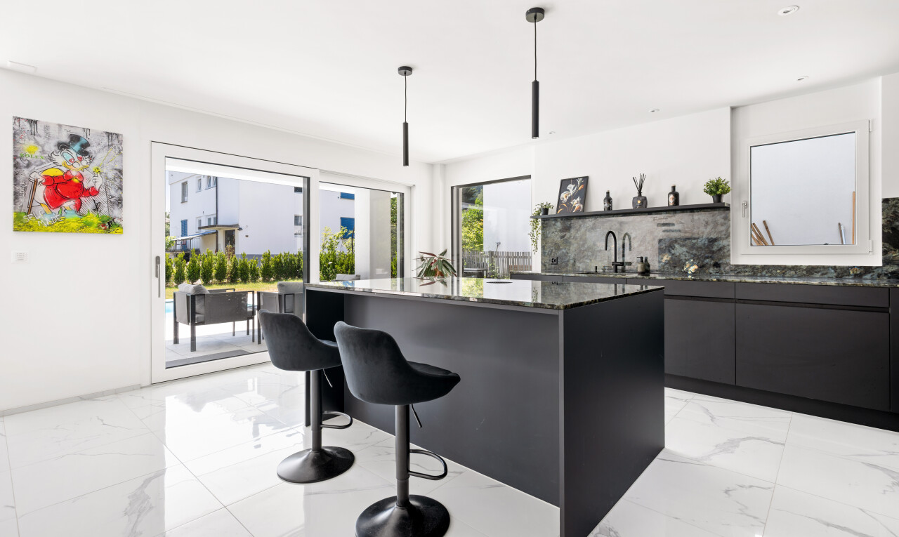 kitchen with modern cabinets, a kitchen island with sink, a breakfast bar area, dark stone countertops, and hanging light fixtures