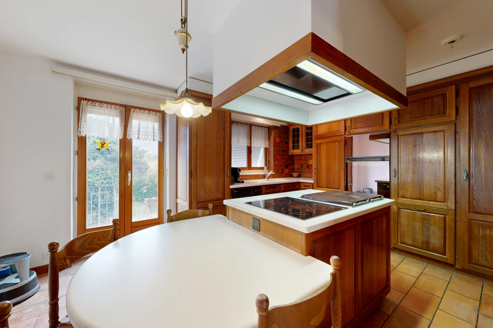 kitchen with island range hood, light countertops, wood finish cabinets, glass insert cabinets, and access to outside