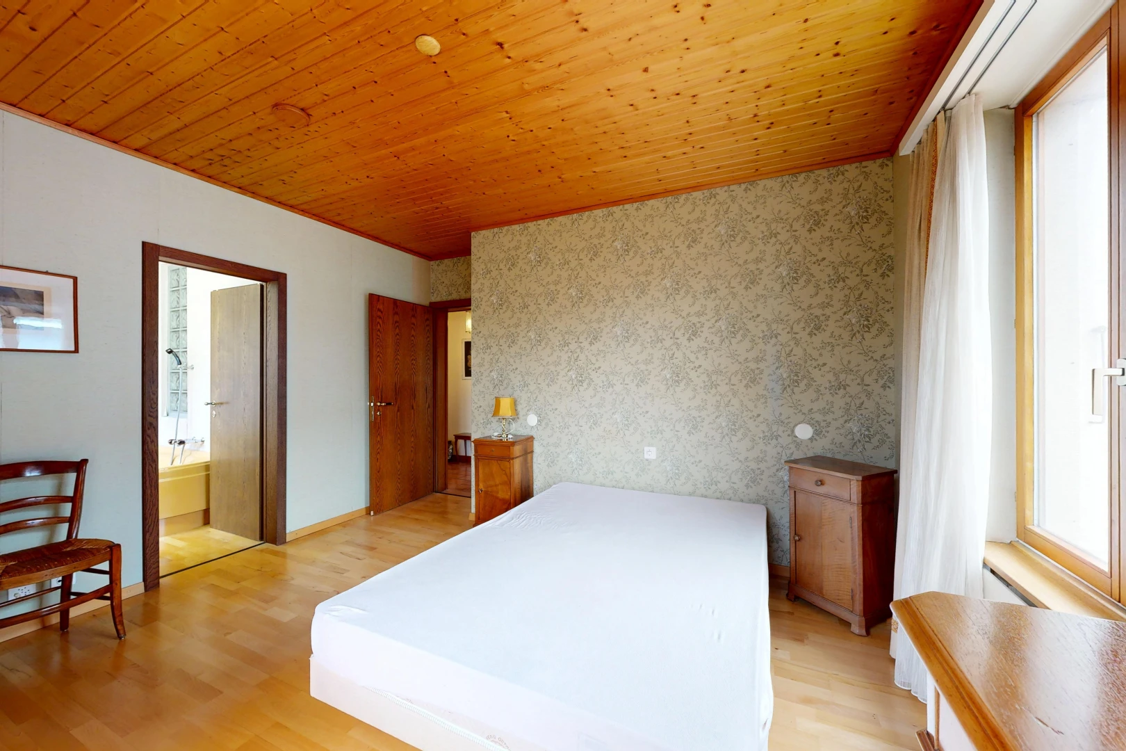 room featuring wood ceiling, light wood-style floors, wallpapered walls, ensuite bathroom, and an accent wall