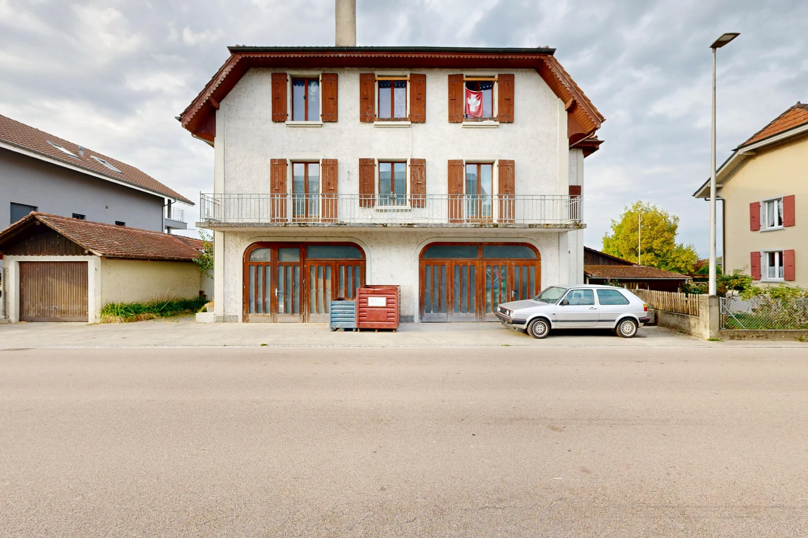 view of property featuring street lights, a chimney, a balcony, and stucco siding