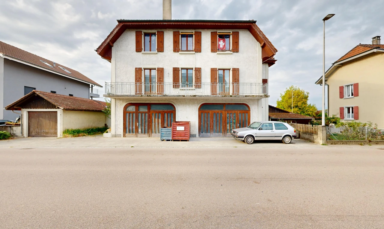 view of property featuring street lights, a chimney, a balcony, and stucco siding
