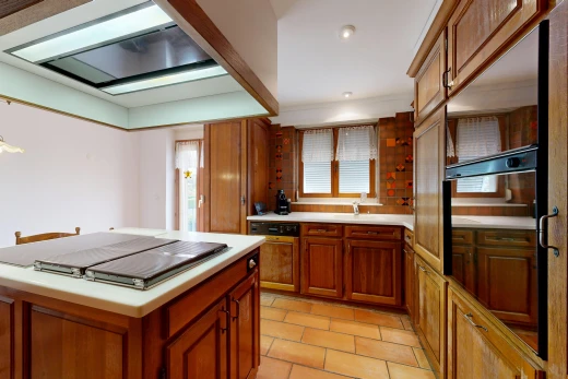 kitchen featuring ventilation hood, wood finish cabinetry, light countertops, recessed lighting, and black oven