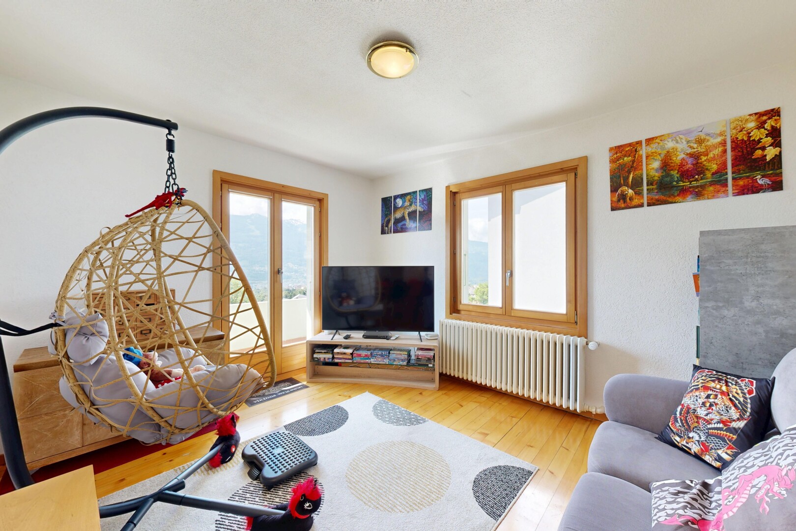 salon avec sol en finition bois, wood finish floor, radiateur, télévision, et inside property