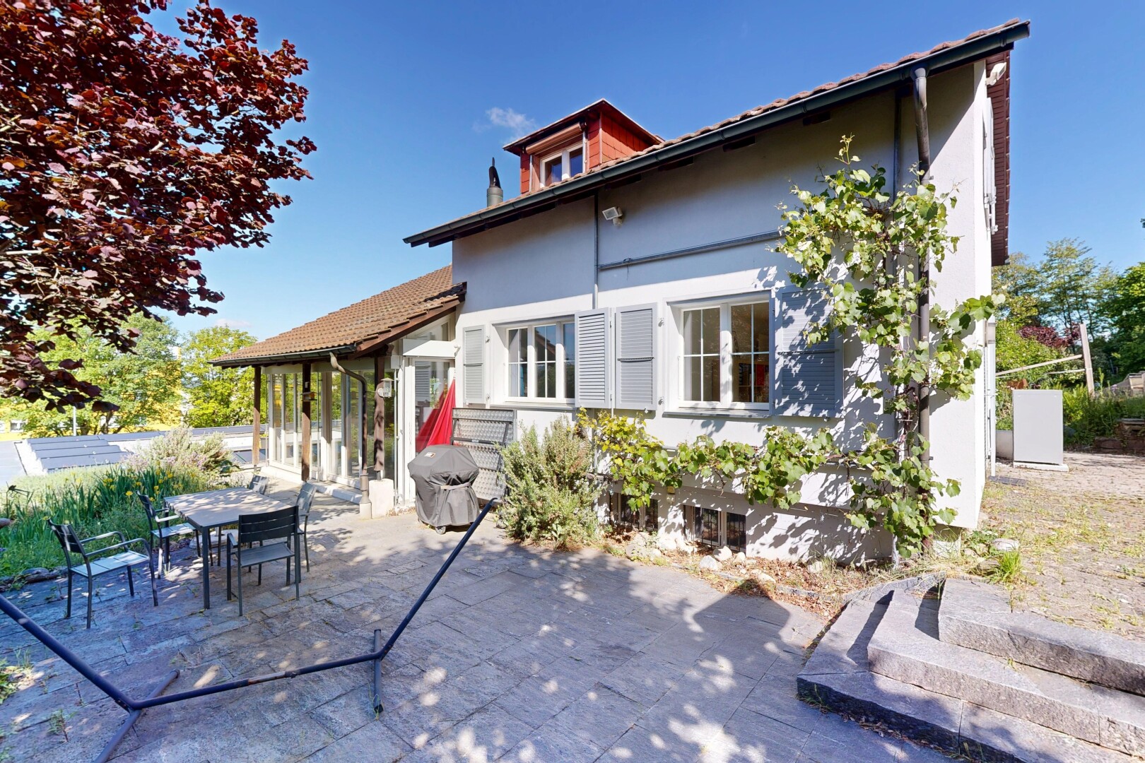 façade avec property visible, coin repas extérieur, terrasse, bardage en stuc, et toit mansardé