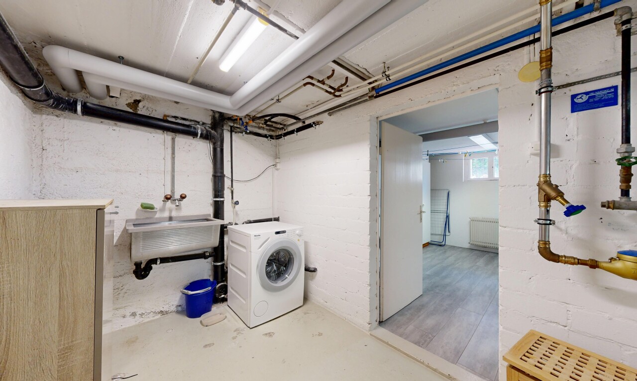 buanderie avec sol en béton, concrete floor, light floor, lave-linge et sèche-linge, et sous-sol