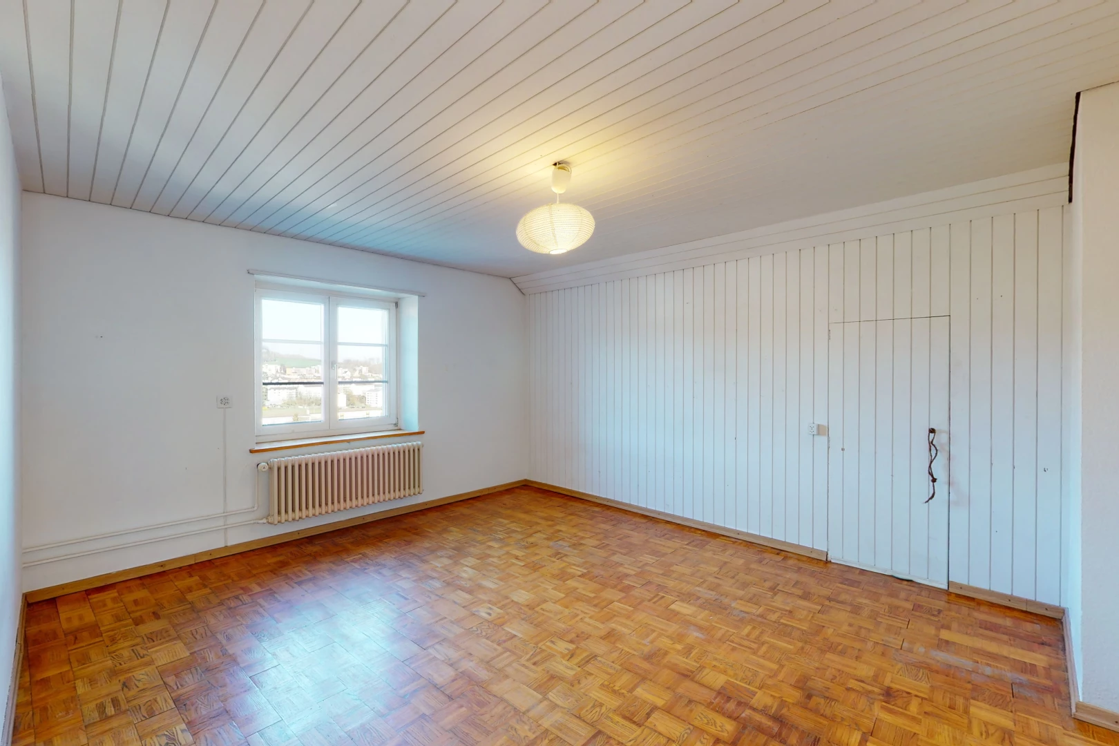 chambre vide avec parquet, lumière naturelle, et radiateur