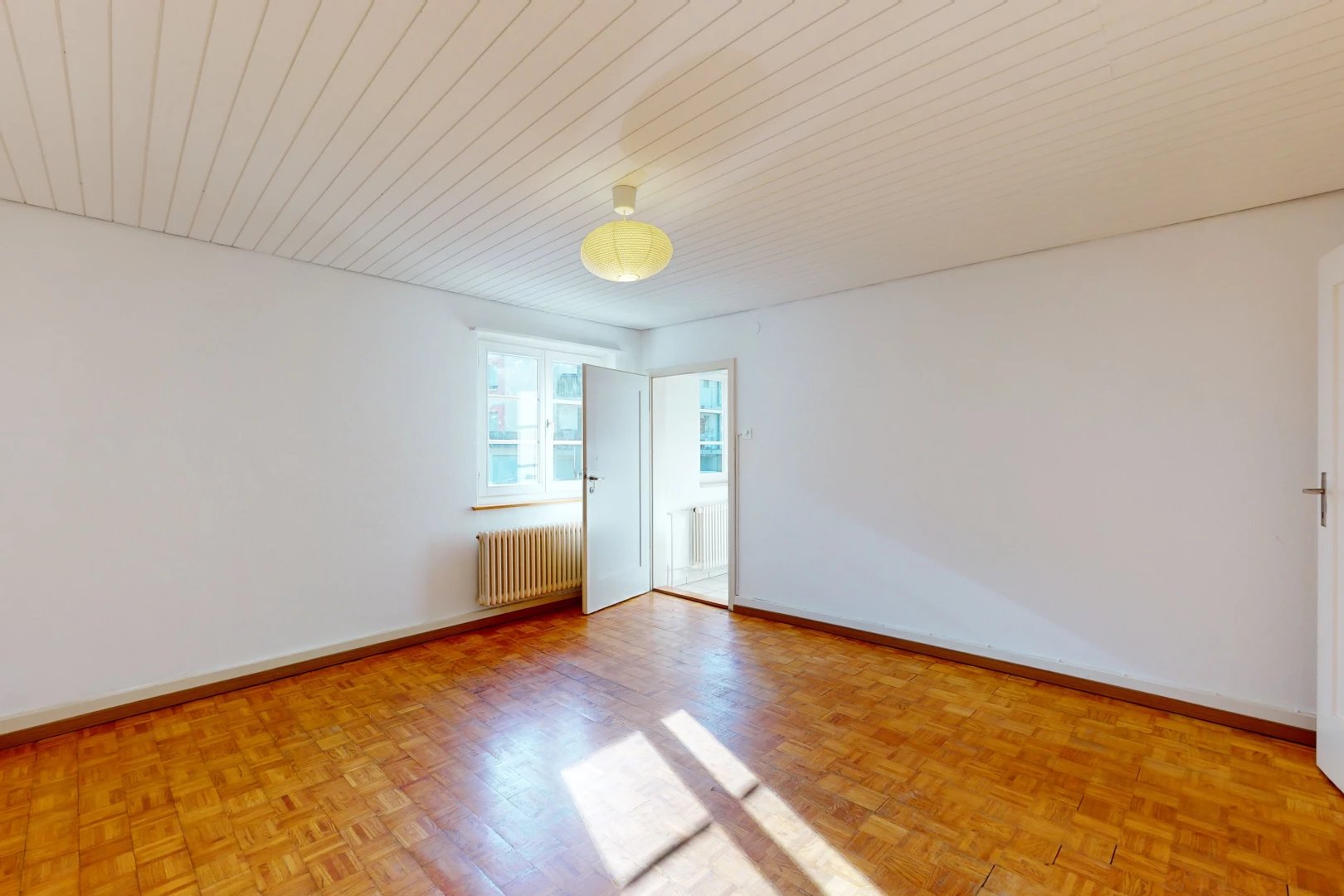 chambre vide avec parquet, lumière naturelle, et radiateur