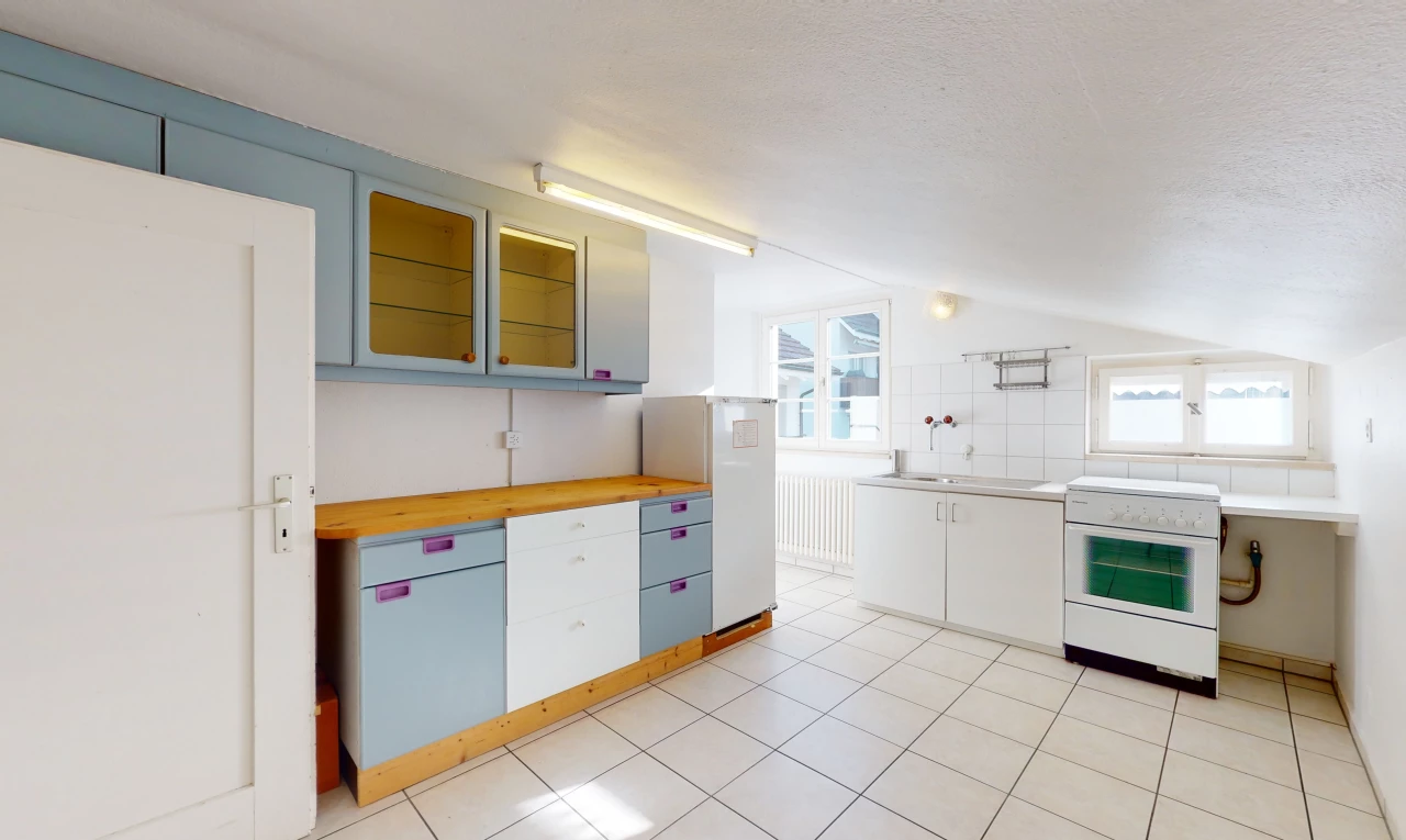 cuisine avec lumière naturelle, carrelage, four intégré, meubles blancs, plan de travail clair, et sol clair