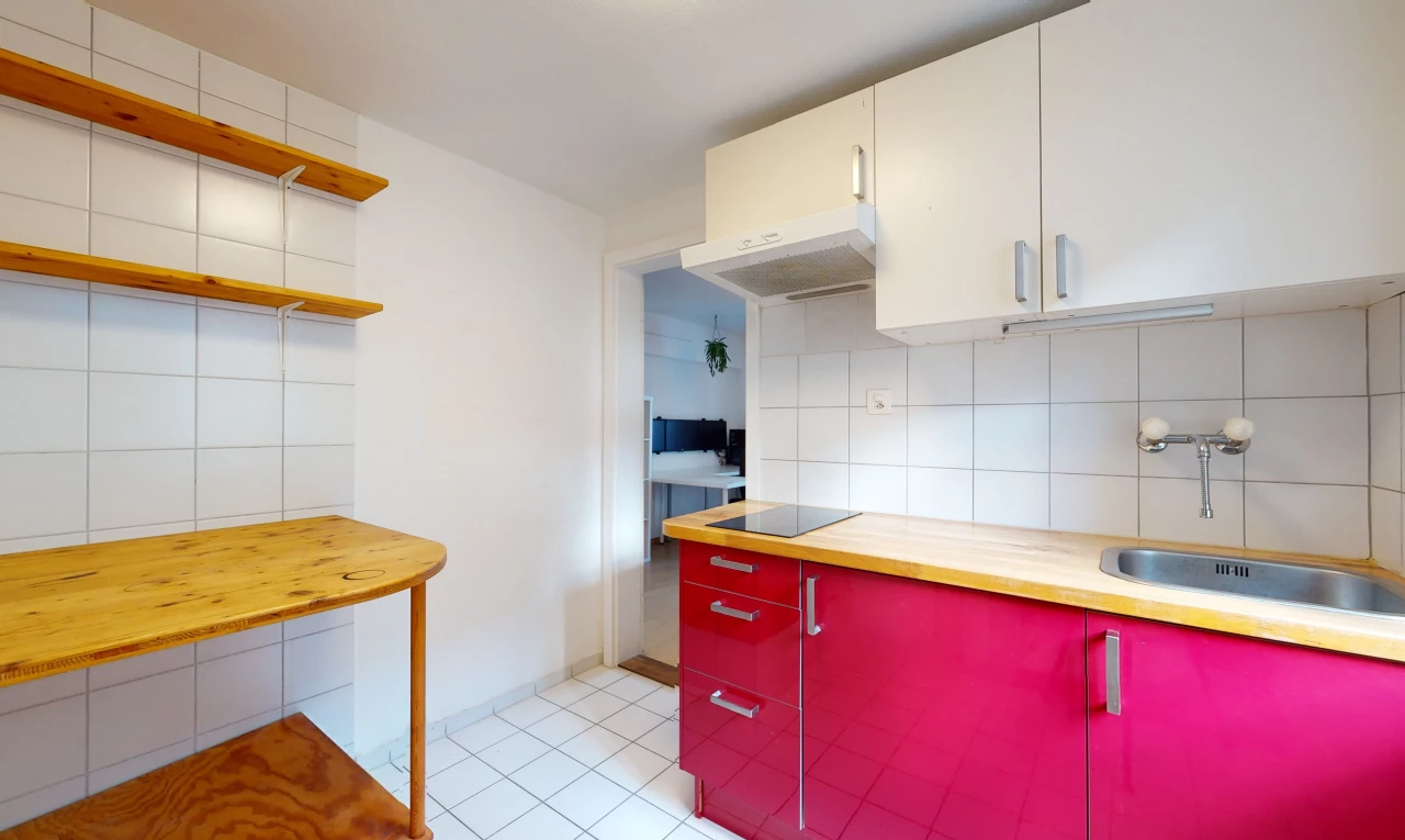 cuisine avec carrelage, cuisinière électrique, hotte, sol clair, plan de travail clair, et meubles blancs