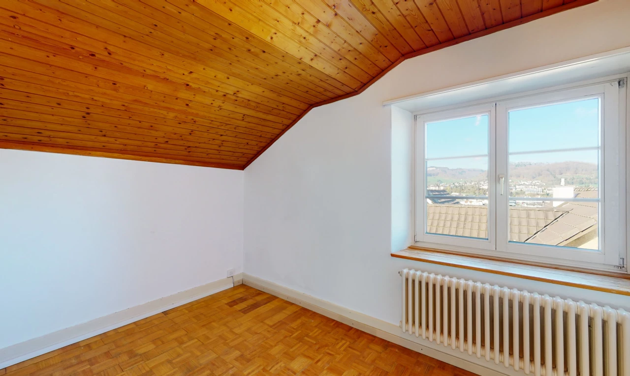 chambre bonus avec parquet, plafond voûté, lumière naturelle, et radiateur