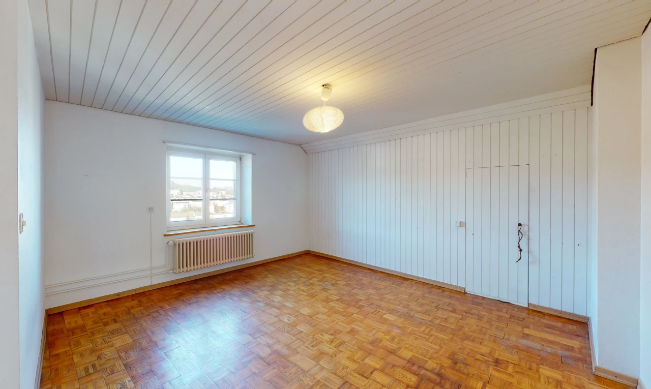 chambre vide avec parquet, lumière naturelle, et radiateur