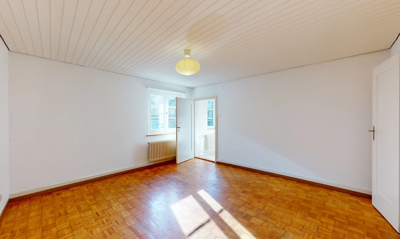 chambre vide avec parquet, lumière naturelle, et radiateur