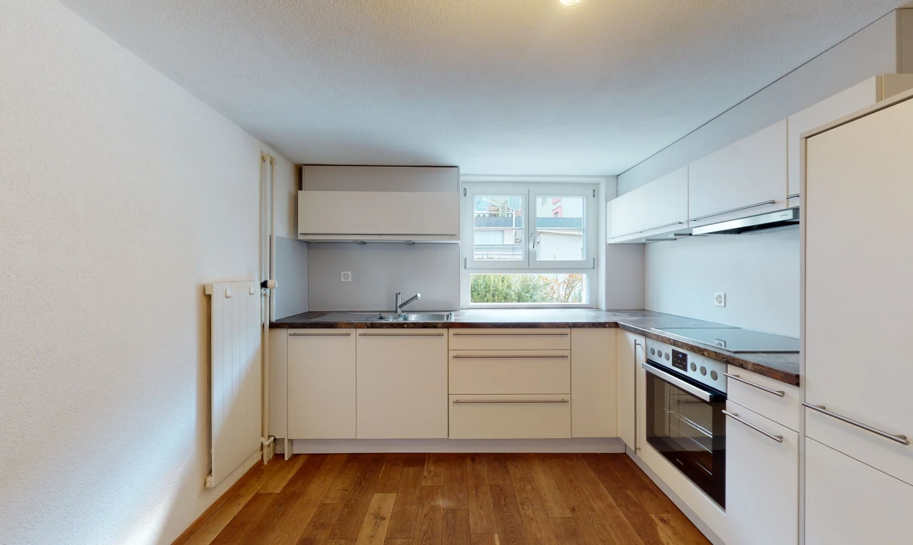 cuisine avec parquet, lumière naturelle, four, hotte, cuisinière électrique, meubles blancs, et sol clair