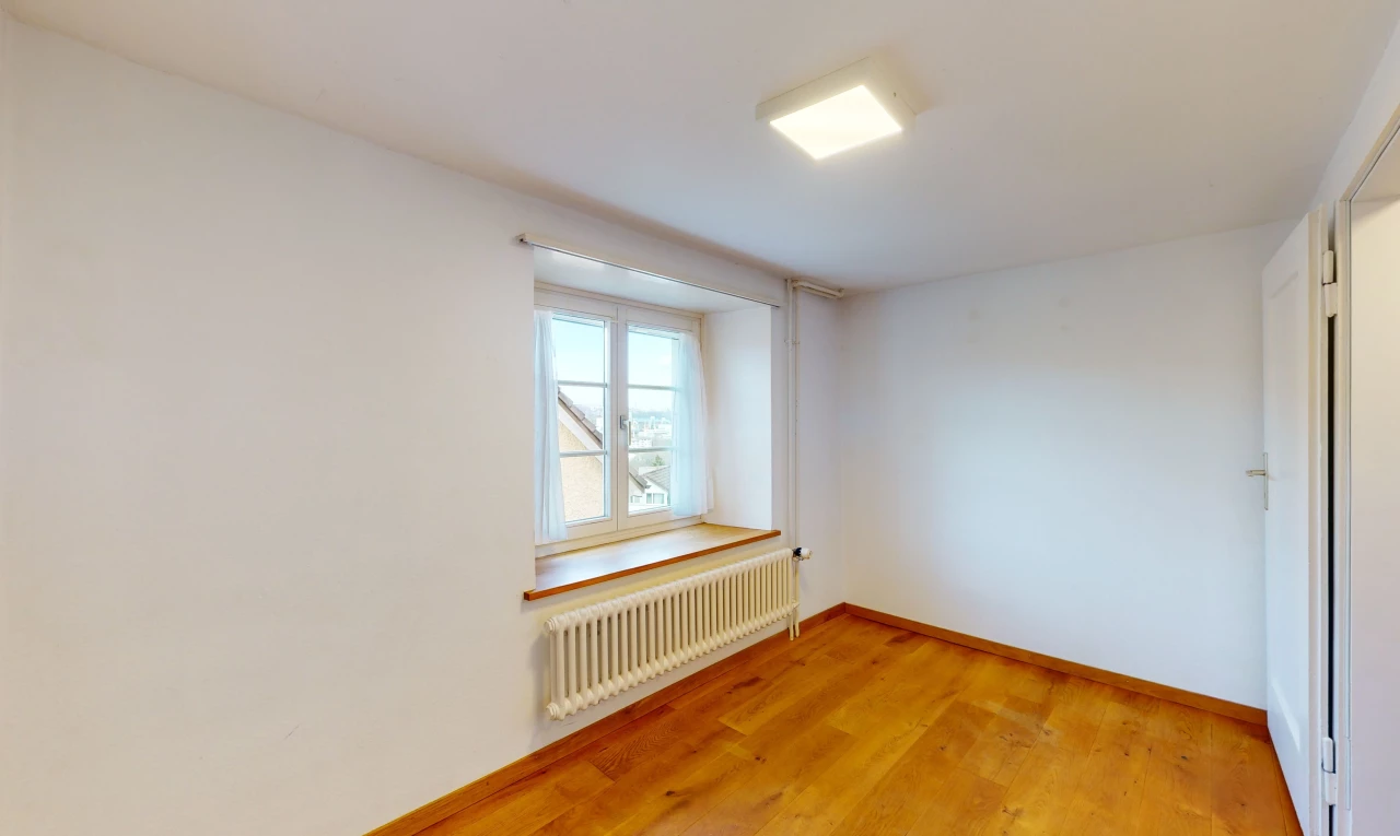 chambre vide avec parquet, lumière naturelle, et radiateur