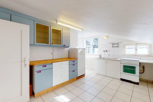 cuisine avec lumière naturelle, carrelage, four intégré, meubles blancs, plan de travail clair, et sol clair