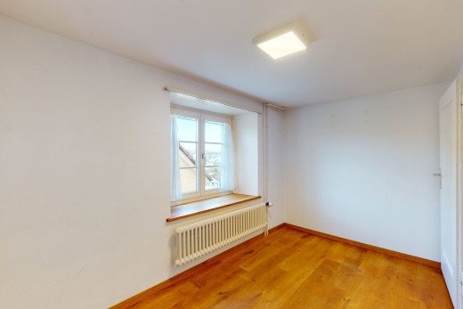 chambre vide avec parquet, lumière naturelle, et radiateur