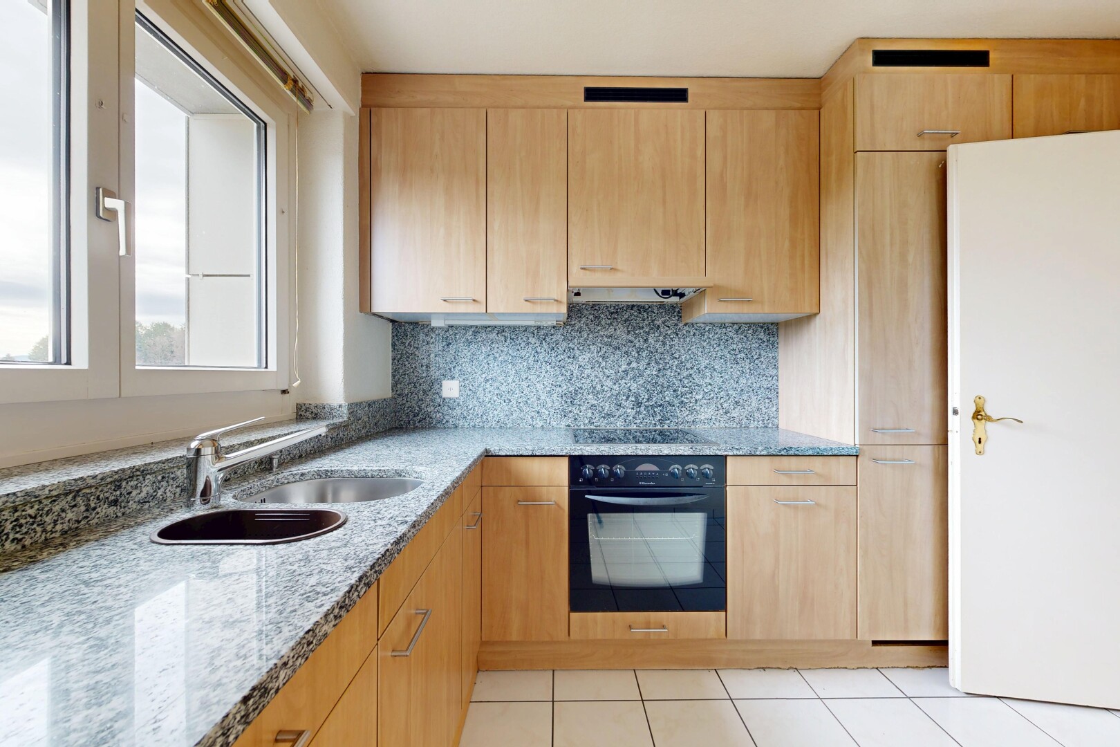 kitchen featuring light wood finish cabinetry, light stone counters, black appliances, tasteful backsplash, and light tile patterned floors