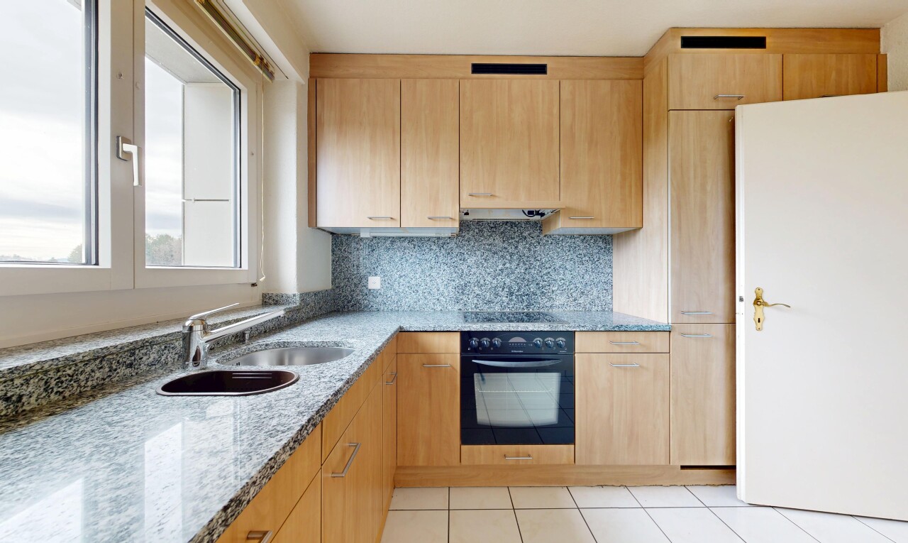 kitchen featuring light wood finish cabinetry, light stone counters, black appliances, tasteful backsplash, and light tile patterned floors