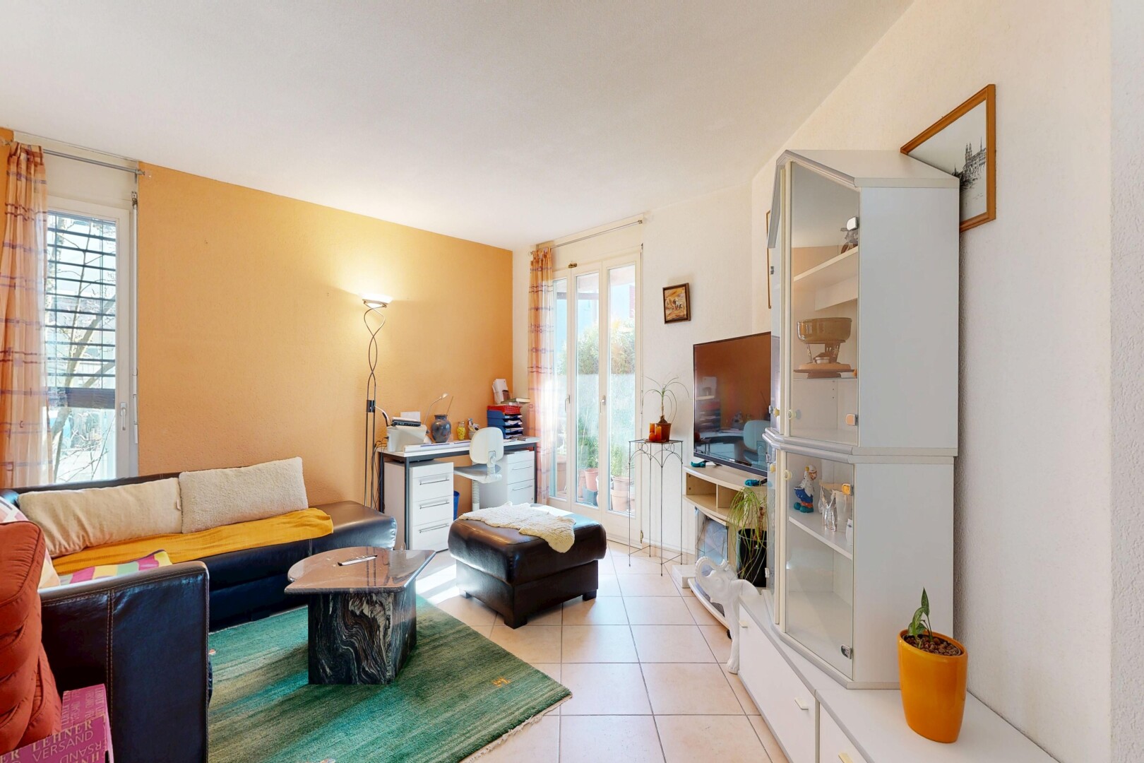salon avec inside property, télévision, cloison sèche, drywall, et sol en carrelage