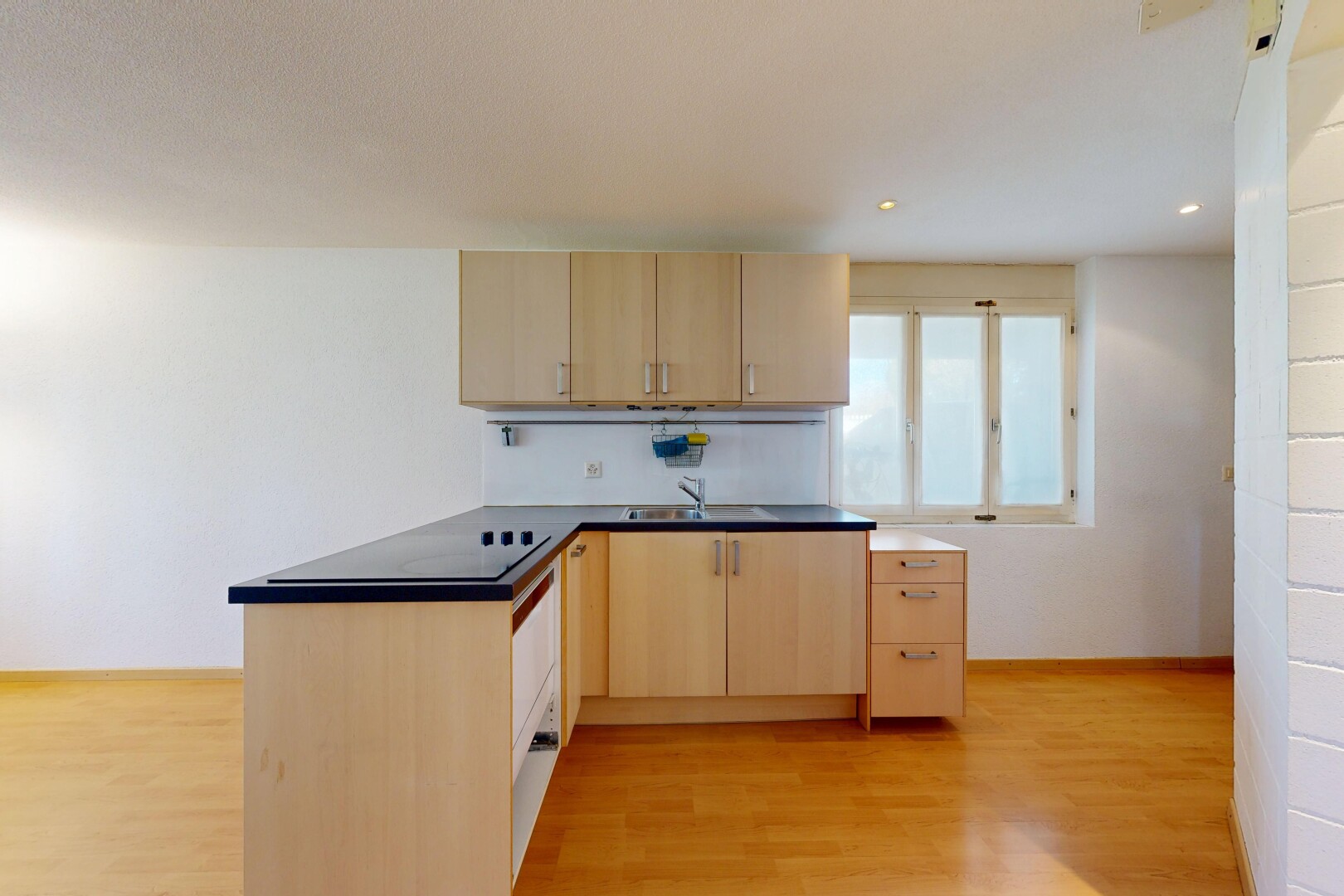 cuisine avec armoires marron clair, light brown cabinets, plans de travail, dark countertops, et péninsule de cuisine
