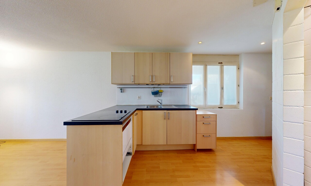 cuisine avec armoires marron clair, light brown cabinets, plans de travail, dark countertops, et péninsule de cuisine