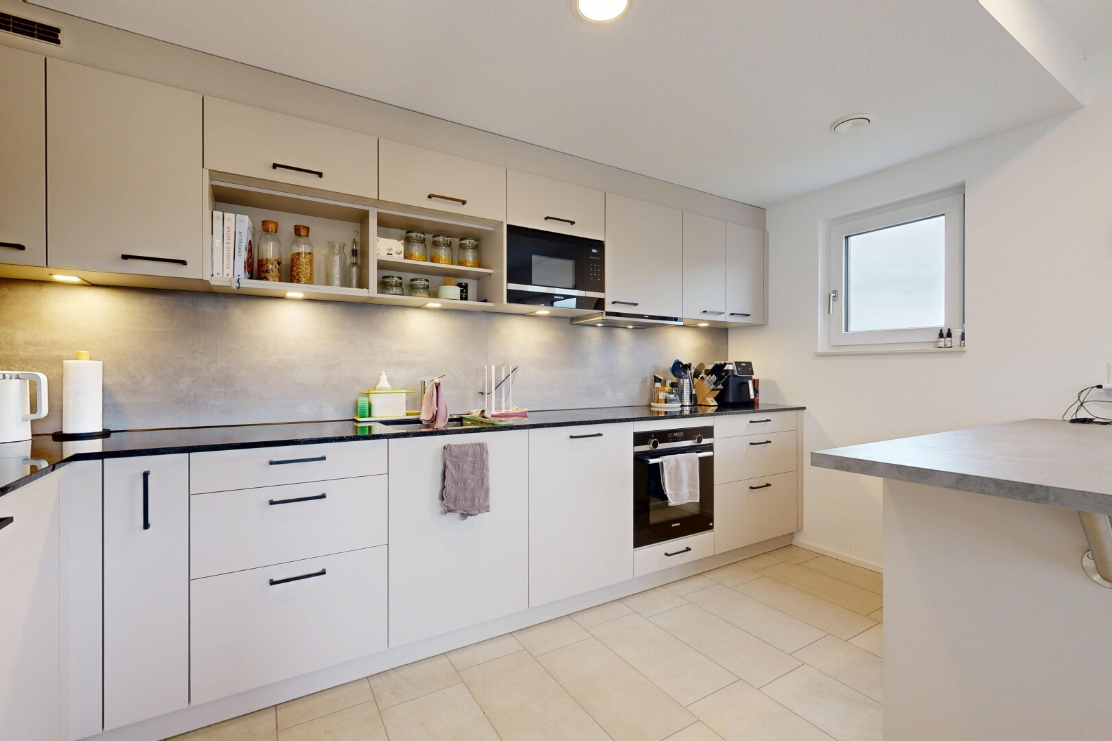 cuisine avec four, light floor, plans de travail, dark countertops, et lumière naturelle