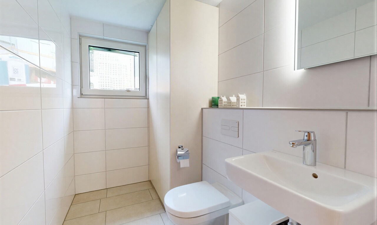salle de bains avec tile wall, mur en carrelage, toilette, natural light, et lumière naturelle
