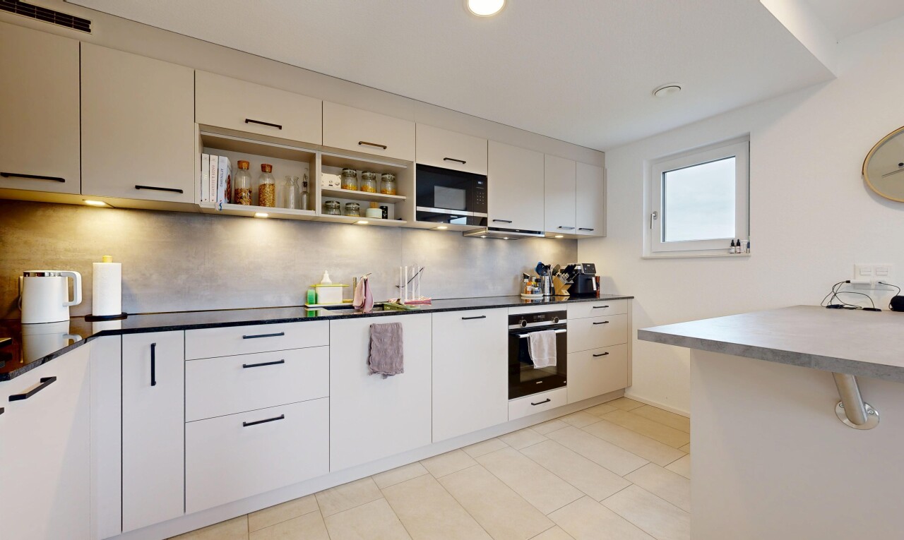 cuisine avec four, light floor, plans de travail, dark countertops, et lumière naturelle