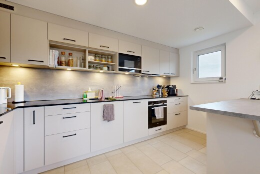 cuisine avec four, light floor, plans de travail, dark countertops, et lumière naturelle