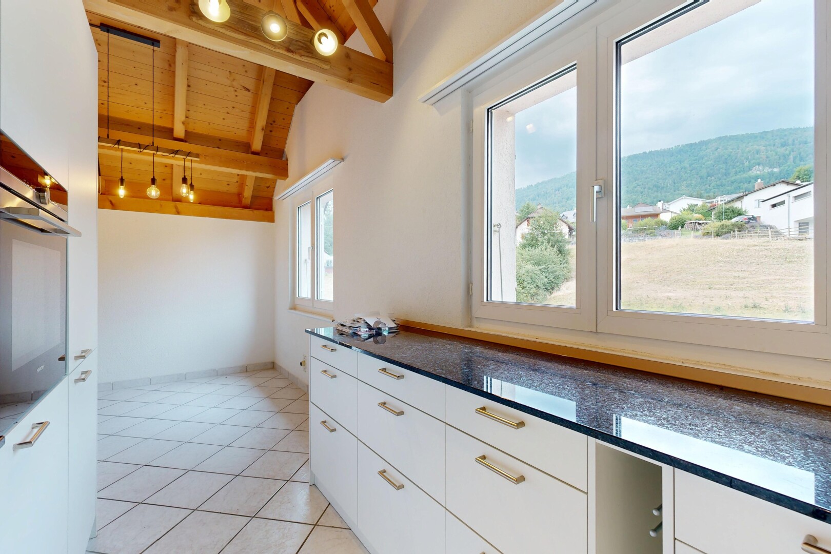 cuisine avec dark countertops, éclairage sur rail, armoires blanches, white cabinets, et vaulted ceiling