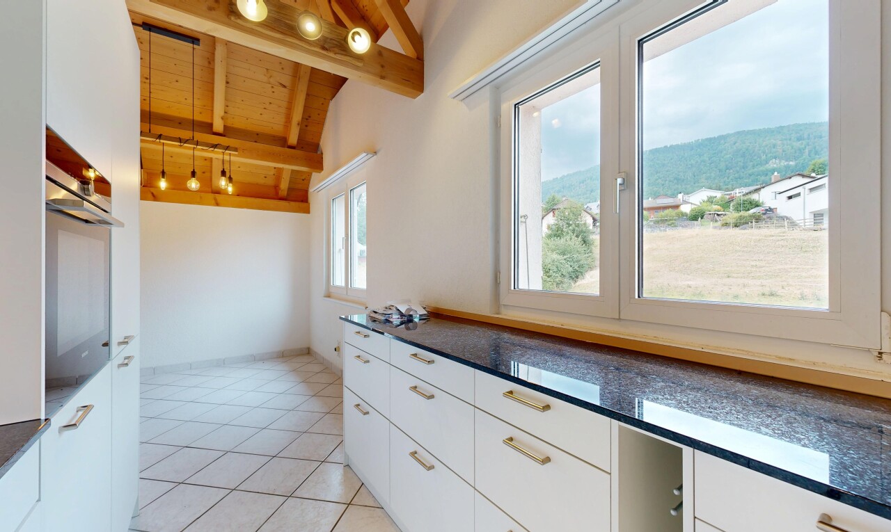 cuisine avec dark countertops, éclairage sur rail, armoires blanches, white cabinets, et vaulted ceiling