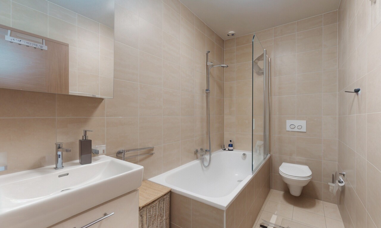 salle de bains avec tile wall, mur en carrelage, douche-bain combinés, inside property, et lavabo (ou coiffeuse selon le contexte)