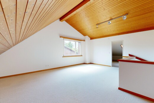 empty room with a wood ceiling with exposed beams, light colored carpet, and track lighting
