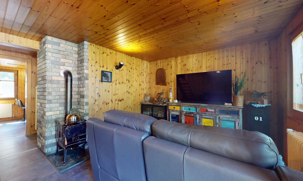salon avec plafond de bois, mur en bois, télévision, et mur en briques