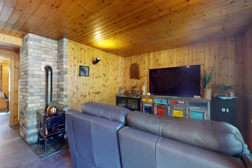 salon avec plafond de bois, mur en bois, télévision, et mur en briques