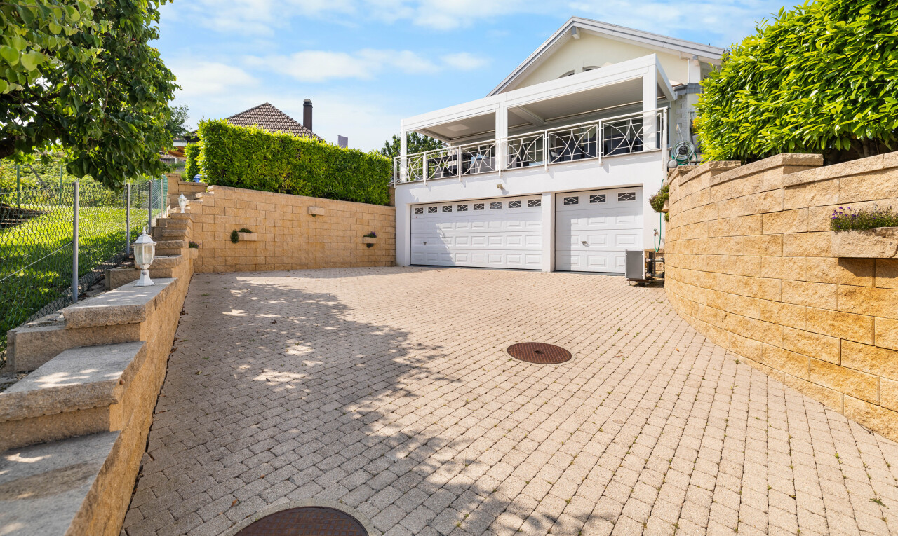 view of home with an attached garage, driveway, and a balcony