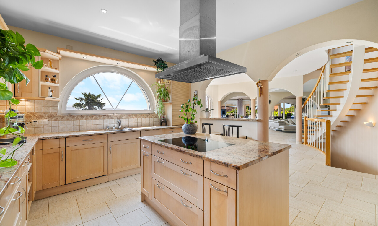 kitchen featuring light brown cabinetry, island exhaust hood, tasteful backsplash, arched walkways, and light stone countertops