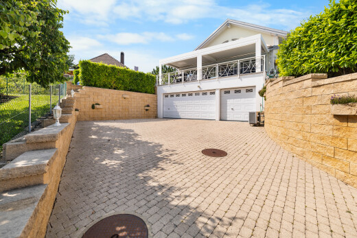 view of home with an attached garage, driveway, and a balcony