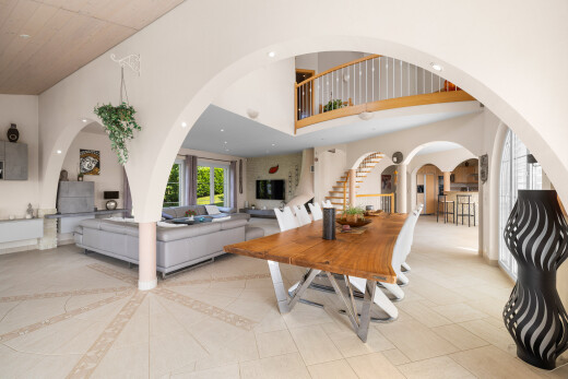 dining room featuring a towering ceiling, stairway, and arched walkways