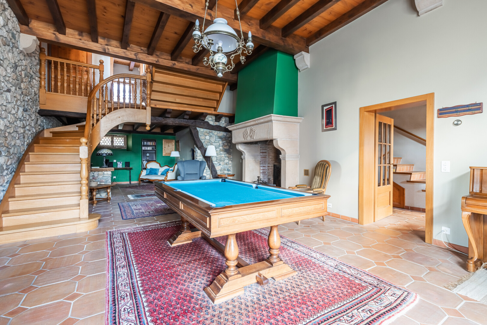 salon avec plafond haut, high ceiling, escaliers, billard, et stone wall