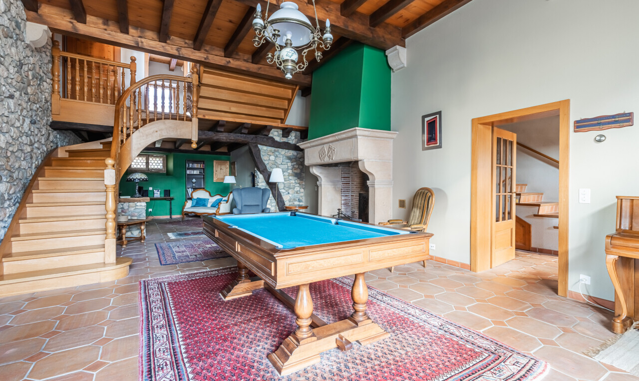 salon avec plafond haut, high ceiling, escaliers, billard, et stone wall