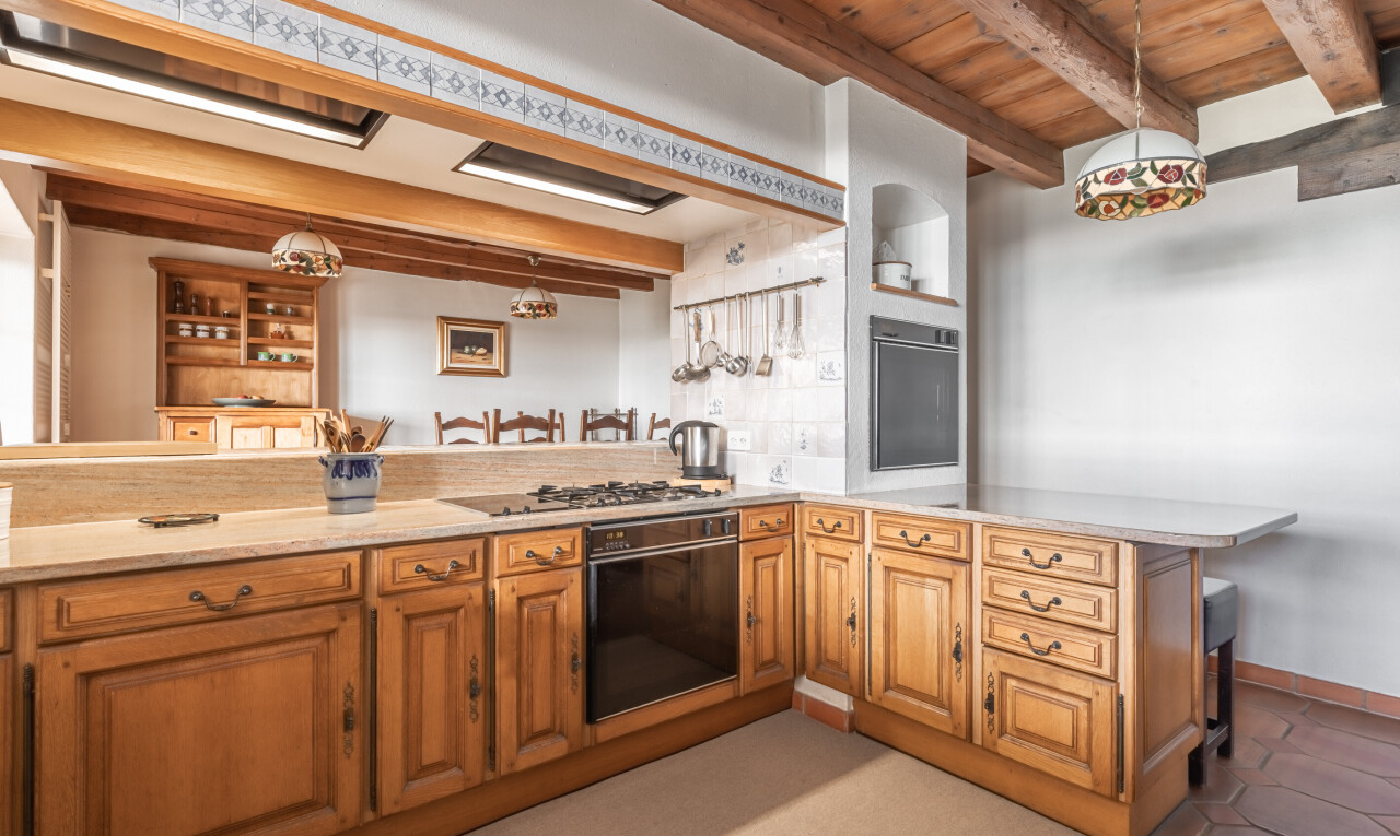 cuisine avec péninsule de cuisine, plafond à poutres, beamed ceiling, éclairage suspendu, et four