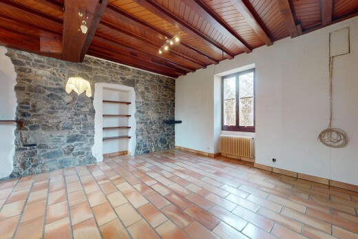 pièce vide avec radiateur, plafond de bois, lumière naturelle, et mur en pierre
