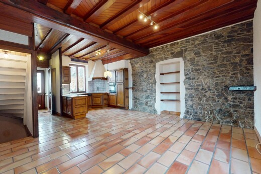 pièce vide avec plafond de bois, lumière naturelle, poutres apparentes, et mur en pierre