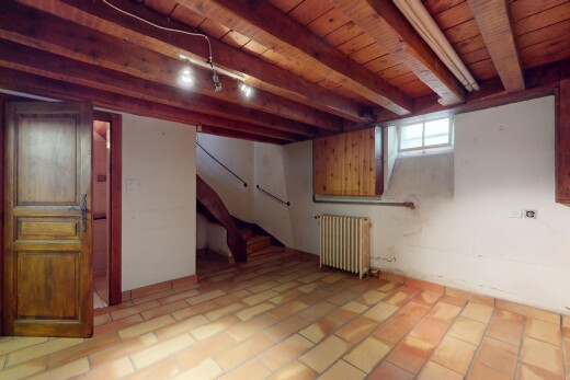 pièce vide avec poutres apparentes, lumière naturelle, radiateur, plafond de bois, et carrelage