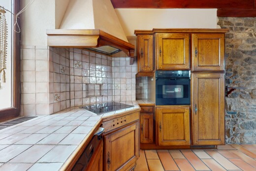 cuisine avec four, hotte, plan de travail en carrelage, et meubles avec moulures
