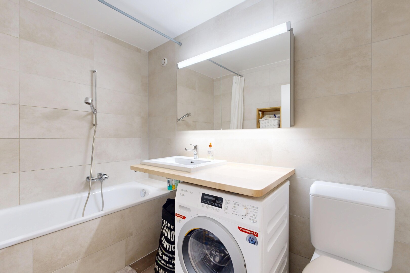 full bath featuring tile walls, washer / clothes dryer, and tiled shower / bath