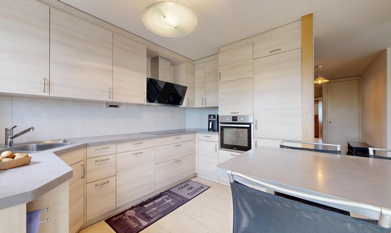 kitchen featuring stainless steel oven, light countertops, light wood finish cabinetry, and black electric stovetop
