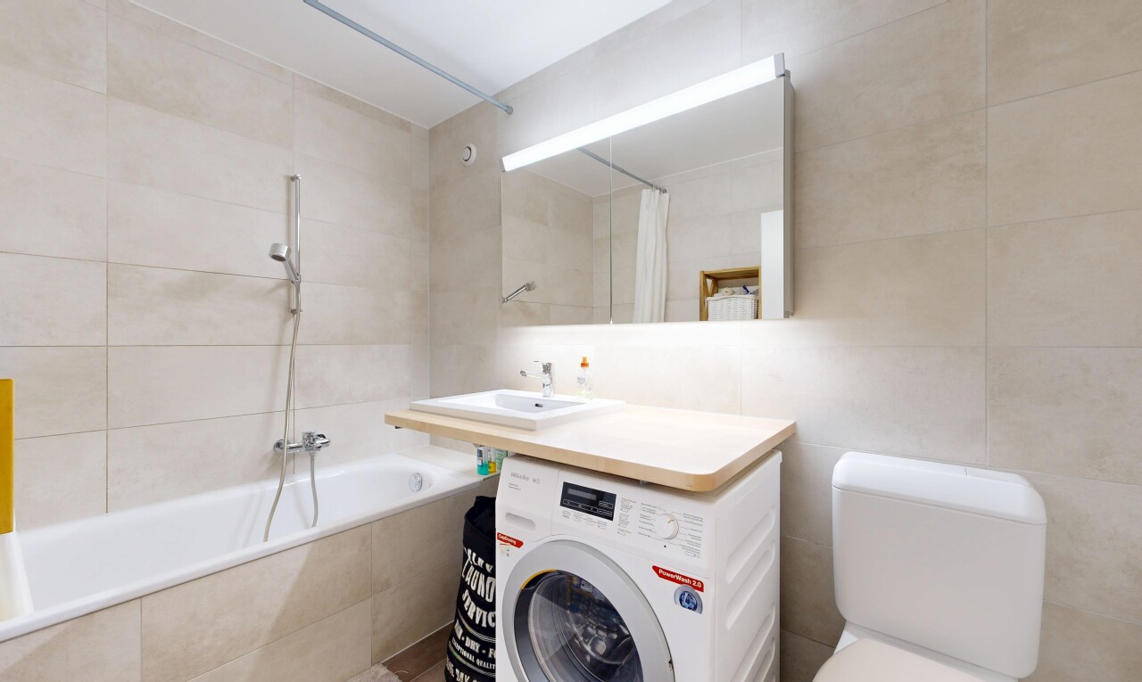 full bath featuring tile walls, washer / clothes dryer, and tiled shower / bath
