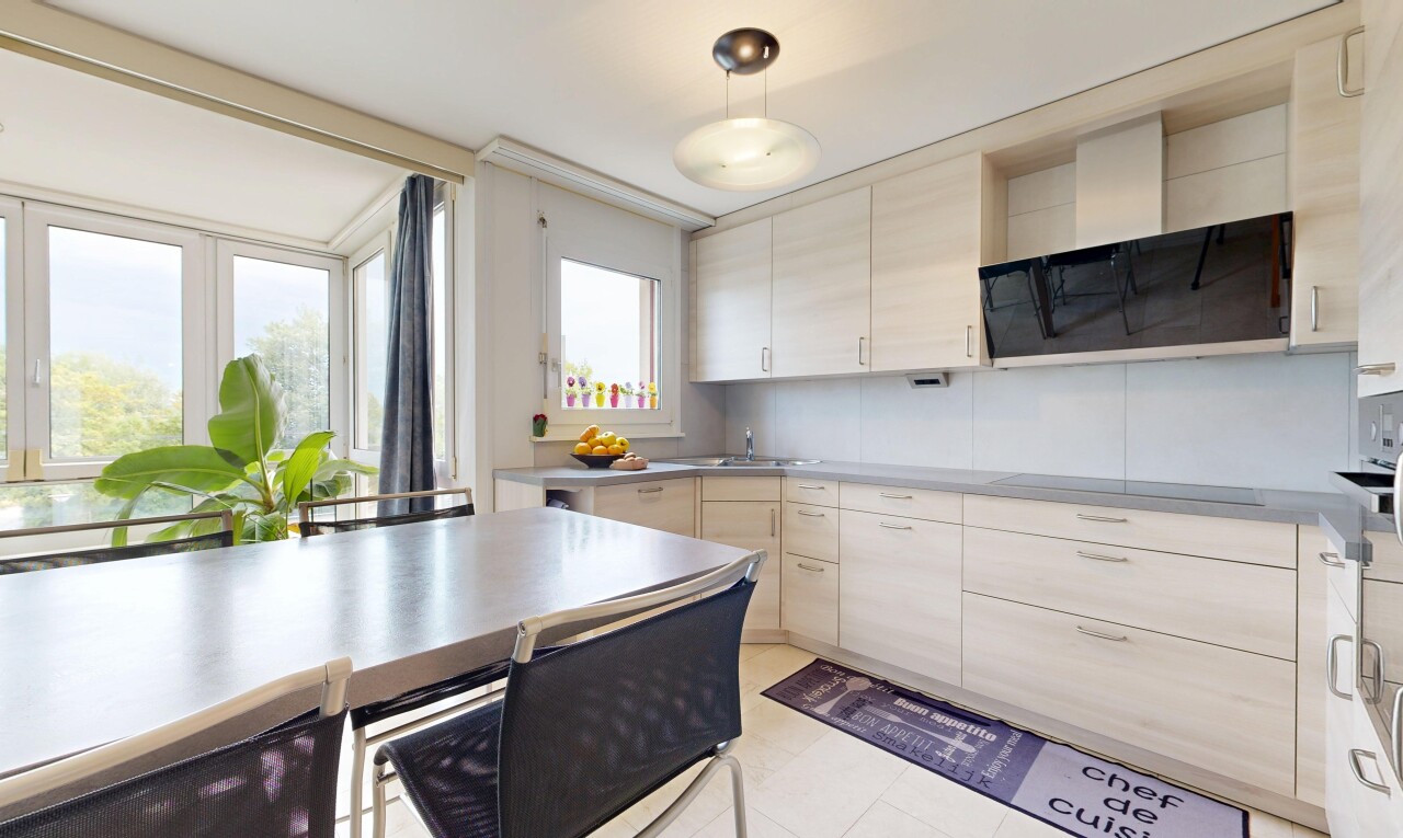 kitchen featuring ventilation hood, hanging light fixtures, stainless steel countertops, light wood finish cabinets, and black electric stovetop